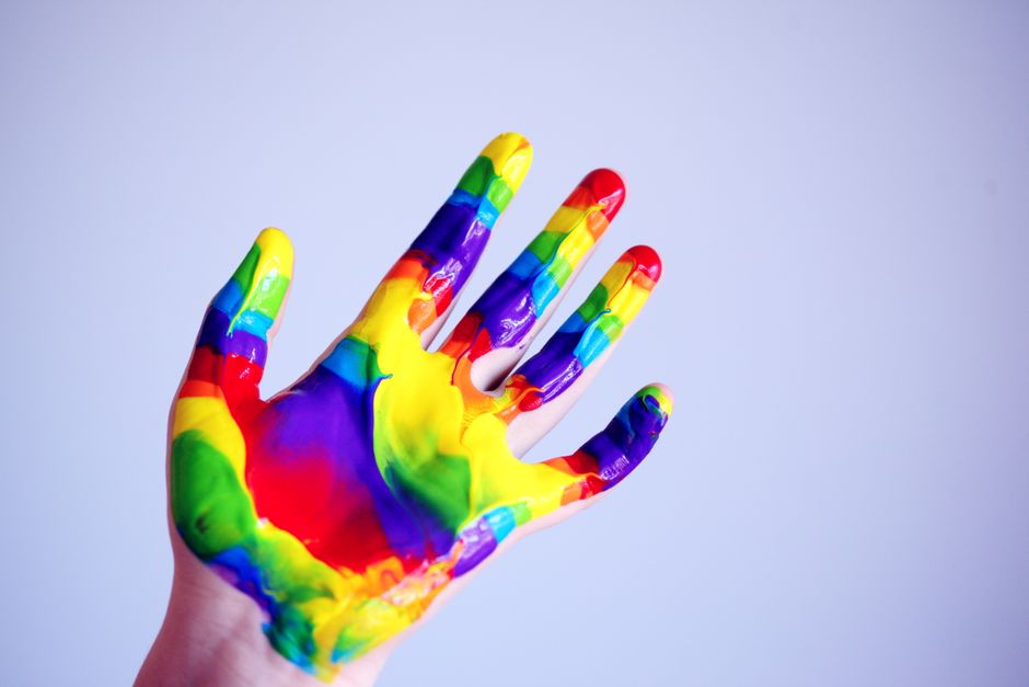 A hand covered in rainbow finger paint