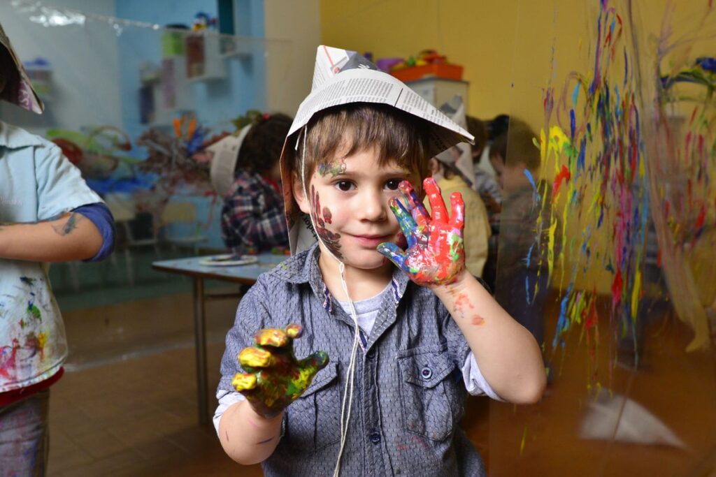Smiling boy showing hands covered in colorful paint